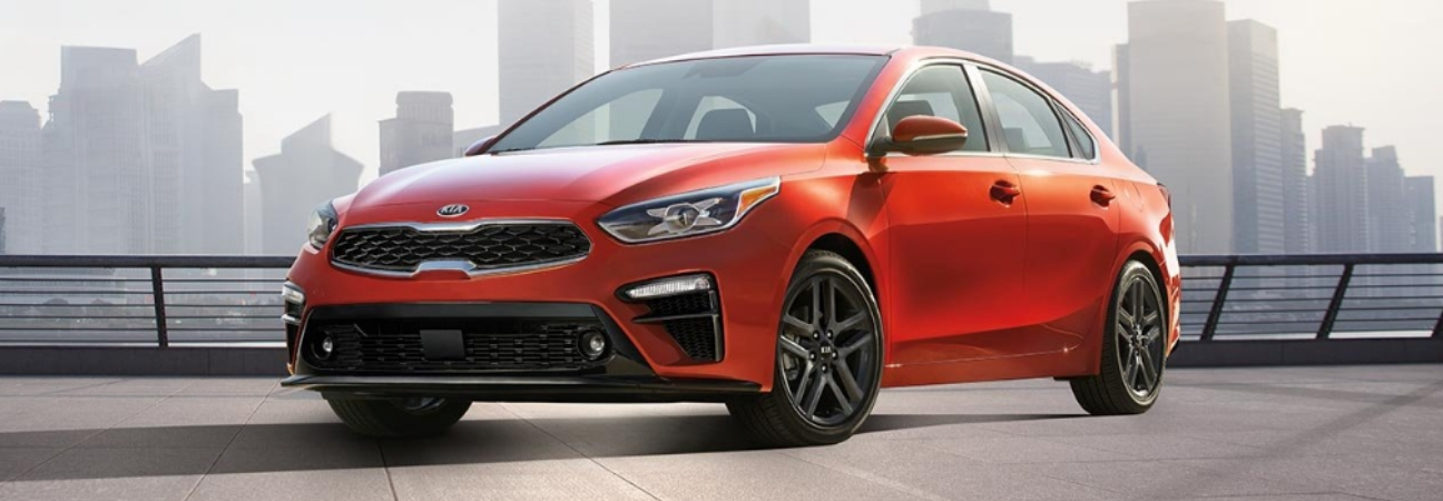 Red 2019 Kia Forte parked in front of city skyline